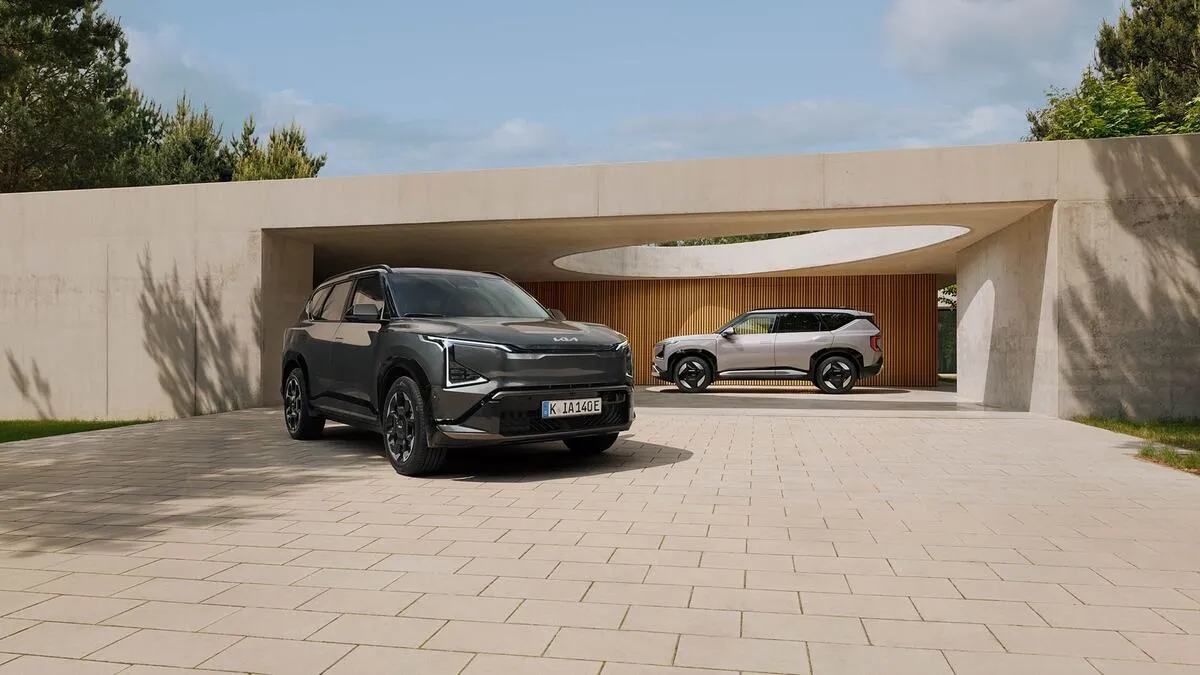 Två Kia EV5 parkerade utomhus vid en villa en solig dag